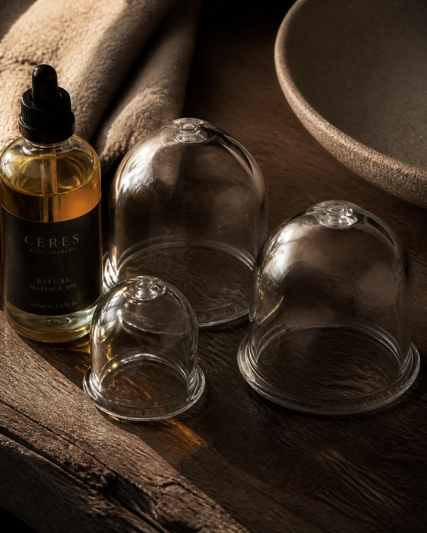 Glass cupping cups and massage oil on dark wood